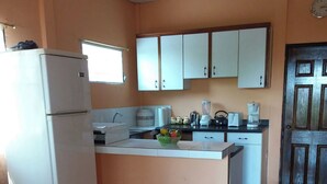 A kitchen with white cabinets, a refrigerator, a sink, and a coffee maker. - Room-el Zonte Tiki Surf, Ocean-view Po (Chiltiupan)