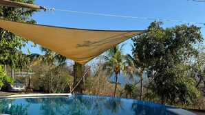A round swimming pool with a shaded area overhead, surrounded by trees and a clear sky. - Room-el Zonte Tiki Surf, Ocean-view Po (Chiltiupan)