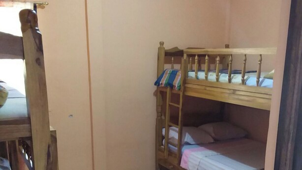 A room with a bunk bed, a wooden chair, and a small table. - Room-el Zonte Tiki Surfer Beds Steps f (Chiltiupan)