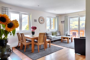 A modern living room with a dining area, large windows, and a view of the outdoors. - Hölderle Damüls (Damüls)