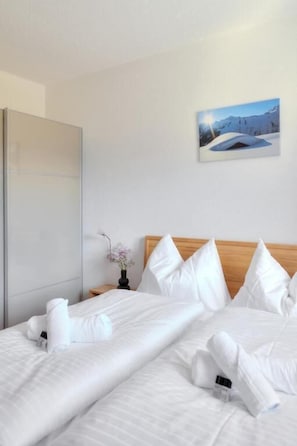 A hotel room with a bed, pillows, a nightstand, a vase with flowers, and a painting on the wall. - Hölderle Damüls (Damüls)