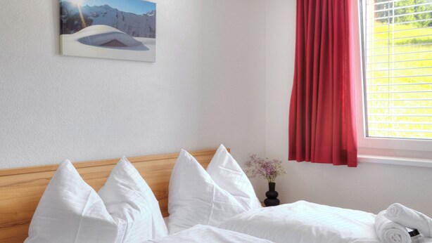 Ein Hotelzimmer mit einem hölzernen Kopfteil, weißer Bettwäsche und einem Wandbild mit einer Berglandschaft.