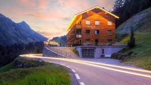 Ein mehrstöckiges Hotel mit Backsteinfassade, gelegen in einer gebirgigen Gegend, durch die eine Straße schlängelt.