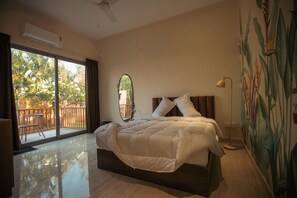 Ein Schlafzimmer mit einem großen Bett, einem Deckenventilator, einer Schiebetür zu einem Balkon und einem Wandgemälde.