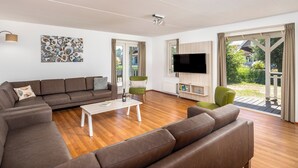 En moderne stue med en sofa, et sofabord, et fladskærms-TV og et maleri på væggen.