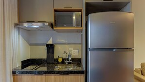 Une cuisine moderne équipée d’un four à micro-ondes encastré, d’un réfrigérateur en acier inoxydable et d’un plan de travail noir.