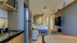 Een moderne kitchenette met een ingebouwde magnetron, een roestvrijstalen koelkast en een gootsteen met kraan.