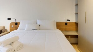Een hotelkamer met een bed, twee nachtkastjes, een lamp en een wandplank.