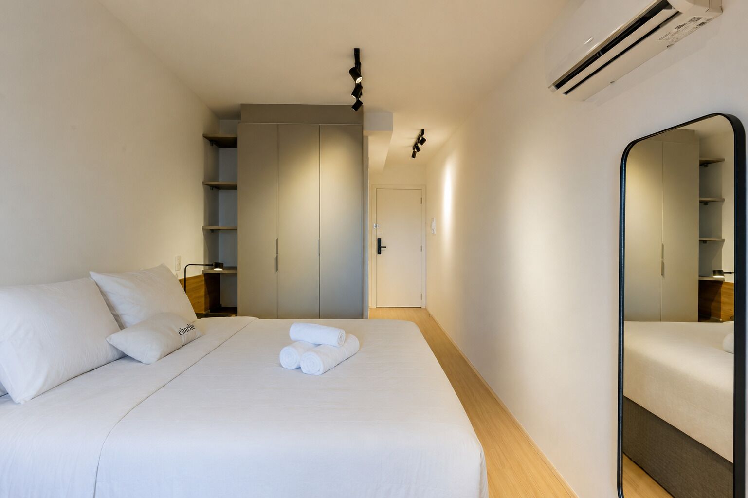Una habitación de hotel con una cama, un armario, un espejo y una puerta.