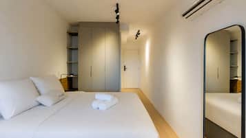 Una habitación de hotel con una cama, un armario, un espejo y una puerta.