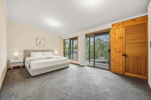 Ein Schlafzimmer mit Bett, Nachttisch und einer großen Schiebetür zum Balkon.