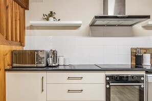 A kitchen with a microwave, toaster, oven, and a white cabinet.