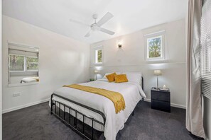 A bedroom with a bed, a ceiling fan, bedside lamps, a nightstand, and a window. - What-A-View Cottage Halls Gap (Halls Gap)