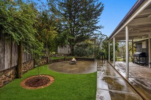 A covered patio area with a fire pit, a barbecue grill, and a stone wall. - What-A-View Cottage Halls Gap (Halls Gap)