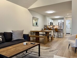 Ein modernes Wohnzimmer mit Sofa, Couchtisch und Essbereich.