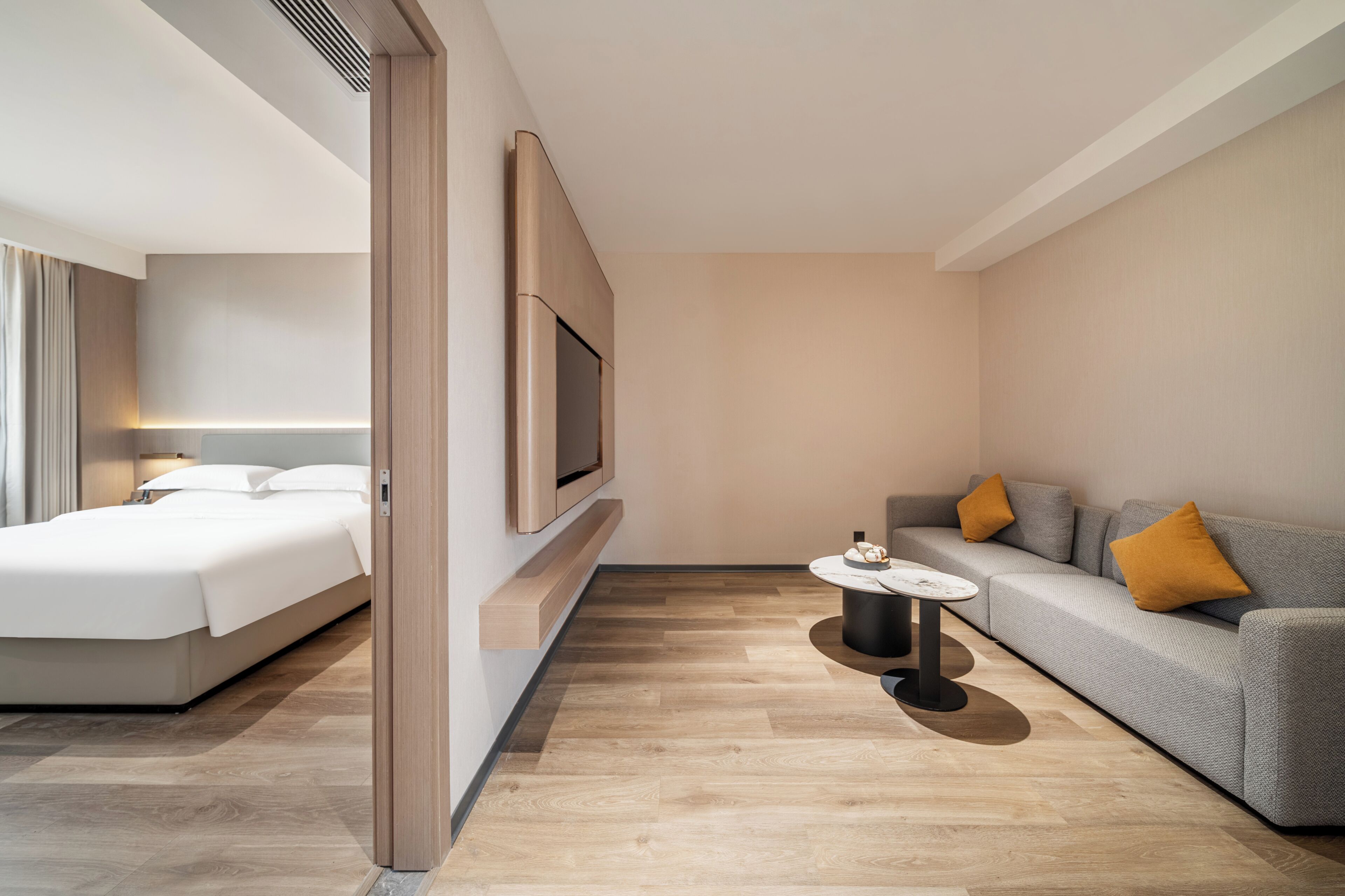 A modern hotel room with a bed, a sofa, a TV, and a small table.