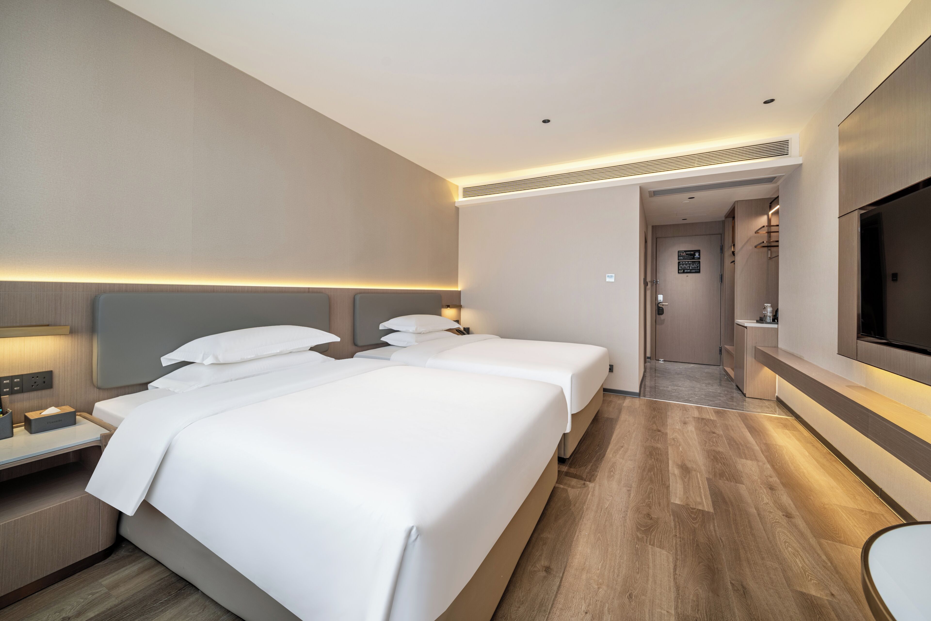 Ett hotellrum med två sängar, en tv, ett skrivbord och ett badrum som syns genom en öppen dörr.
