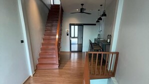 Una escalera conduce a un segundo piso donde se ve un comedor y una cocina al fondo.