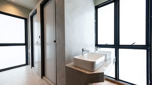 Un baño moderno con un ventanal grande, un lavamanos y una puerta.