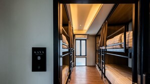 Un pasillo con literas, un letrero que dice 'KAYA HERITAGE B' y vista de una puerta al final.