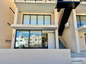 A modern building with large windows, a staircase, and a view of a coastal area. - 2BR Vistana Estates Townhome 5min to Downtown Cabo (El Tezal, Cabo San Lucas)