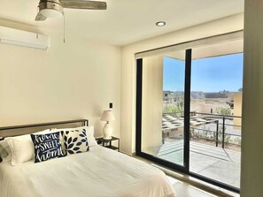 A bedroom with a bed, a nightstand, a lamp, and a view of the outside. - 2BR Vistana Estates Townhome 5min to Downtown Cabo (El Tezal, Cabo San Lucas)
