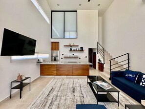 A modern living space with a kitchen, a flat-screen TV, a sofa, and a staircase. - 2BR Vistana Estates Townhome 5min to Downtown Cabo (El Tezal, Cabo San Lucas)