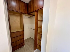 A walk-in closet with wooden shelving and a hanging rod. - 2BR Vistana Estates Townhome 5min to Downtown Cabo (El Tezal, Cabo San Lucas)