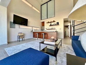 A modern living room with a flat-screen TV mounted on the wall, a coffee table, a sofa, and a staircase leading to an upper level. - 2BR Vistana Estates Townhome 5min to Downtown Cabo (El Tezal, Cabo San Lucas)