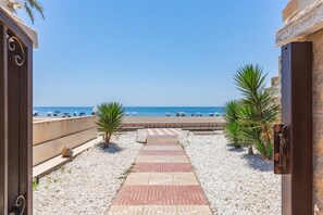 A pathway leading to a beach with umbrellas and people. - 'Club Tropicana' Apartment with Sea View, Private Pool, and Wi-Fi (Roquetas de Mar)