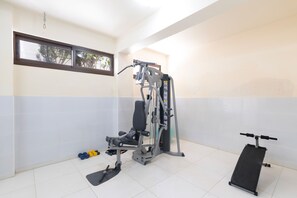 Ein Fitnessraum mit Trainingsgeräten, einer Bank und Kurzhanteln.