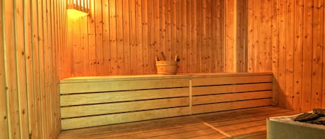 A sauna with wooden benches and a bucket.