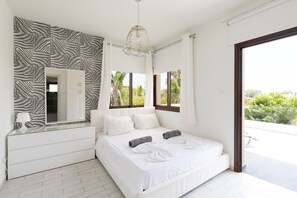 Un dormitorio moderno con una cama grande, un espejo y vistas a zonas verdes.