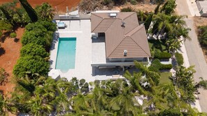 Una vista aerea di una casa moderna con piscina, antenna satellitare e un paesaggio ricco di vegetazione.