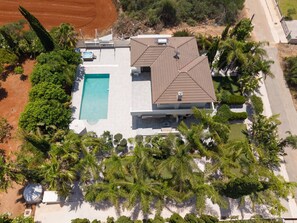 Luftaufnahme eines modernen Hauses mit Swimmingpool, Satellitenschüssel und üppiger Bepflanzung.