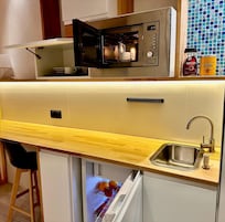 Eine kleine Küche mit integriertem Mikrowellenherd, Spüle und Kühlschrank.