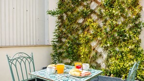 Una mesa con sillas, una disposición para el desayuno y una pared cubierta de plantas trepadoras.
