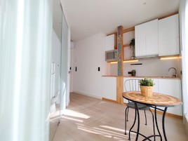 A modern kitchen with white cabinets, a microwave, and a wooden countertop.