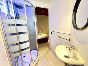 Moderni kylpyhuone, jossa on lasinen suihkuseinä, valkoinen pesuallas ja wc-istuin.