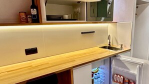 A compact kitchen with a microwave, a sink, and a refrigerator. - Far Home Suites (Madrid)
