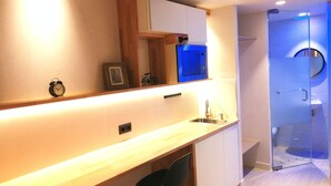 A modern kitchen with a built-in microwave, a sink, and a small seating area with a chair. - Far Home Suites (Madrid)