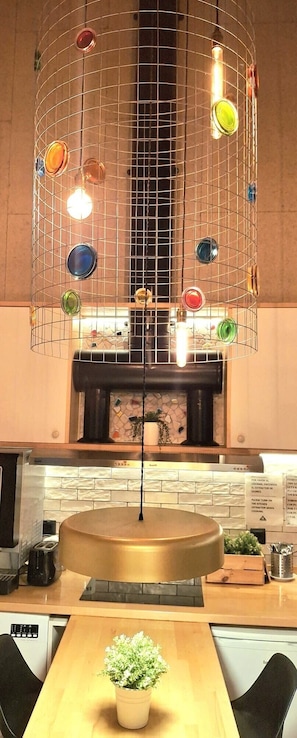 Una cocina con una isla central, una lámpara colgante con esferas de vidrio de colores y una estufa.
