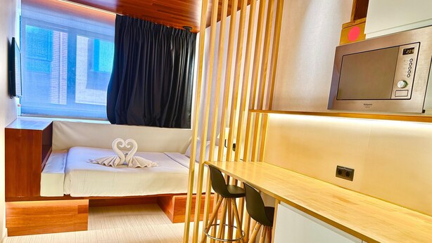 Habitación pequeña con cama, escritorio y televisión.