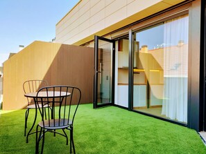 Een modern terras buiten met kunstgras, een tafel en stoelen.