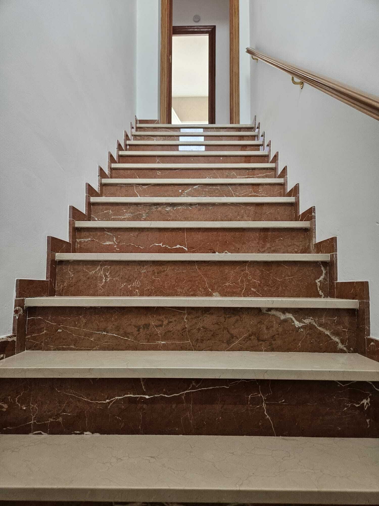A marble staircase with a handrail leading to a doorway.
