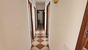Un pasillo con suelo a cuadros, puertas de madera y una lámpara en la pared.