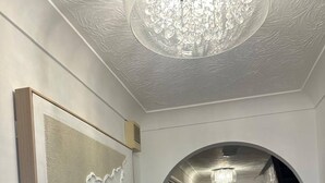 Un passadís amb un candelabrum, una obra d'art emmarcada i una porta al final.