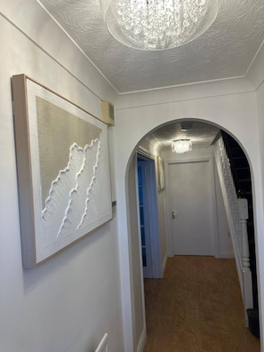 Ein Flur mit einer Chandelüster, einem gerahmten Kunstwerk und einer Tür am Ende.