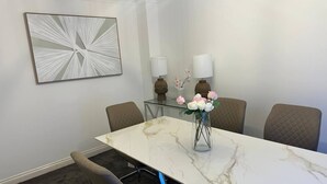 Una sala de conferències amb una taula de marbre, quatre cadires, dues làmpades i una composició floral.
