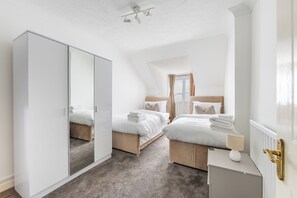 Ein Schlafzimmer mit zwei Betten, einem Kleiderschrank, einem Heizkörper und einem Deckenventilator.